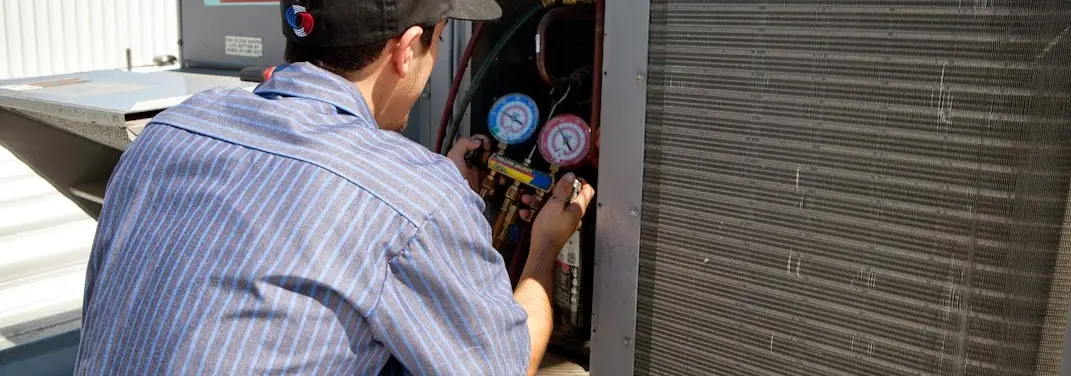 HVAC technician servicing a condenser unit in Makaha