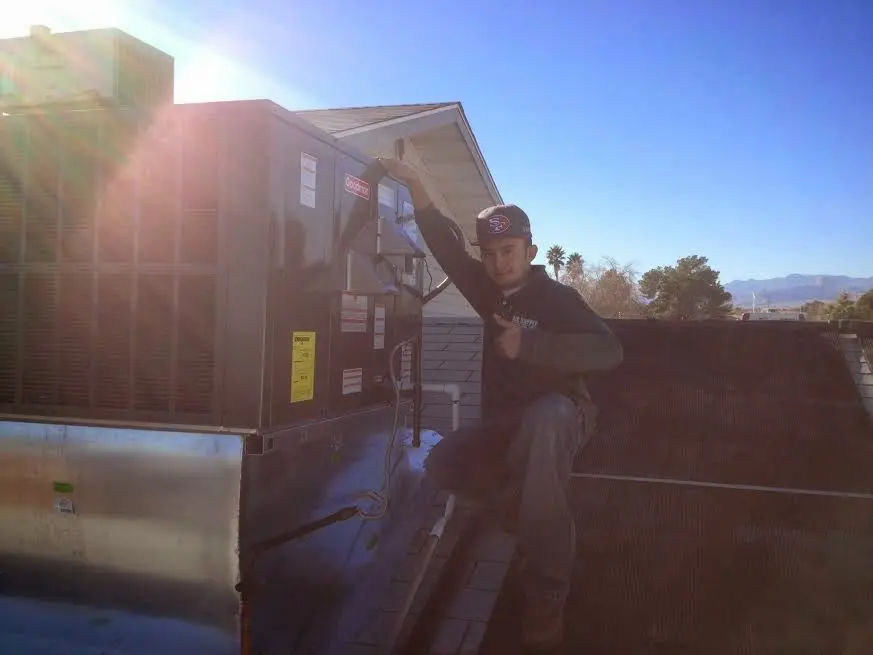 HVAC technician performing AC Tune-Up on a rooftop unit in Makaha